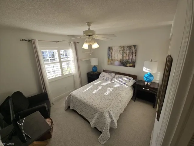 Carpeted bedroom featuring a textured ceiling and ceiling fan