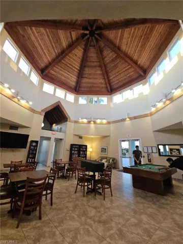 Dining space with a high wooden beamed ceiling and pool table