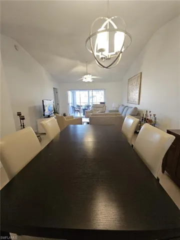 Dining area with a ceiling fan, a chandelier, and lofted ceiling