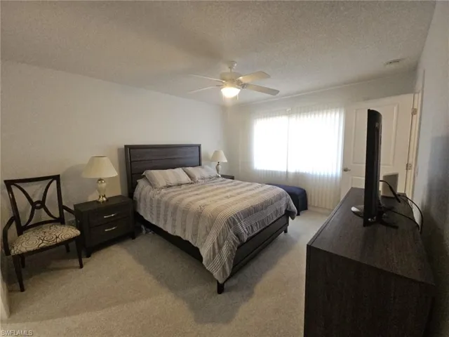 Bedroom with light carpet, a textured ceiling, and ceiling fan