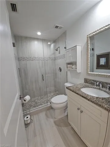 Full bathroom featuring vanity, a stall shower, and light wood-style floors