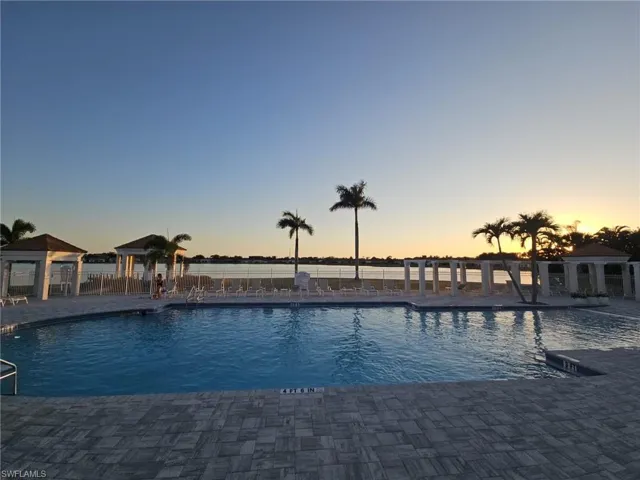 Pool at dusk featuring a patio area and a community pool