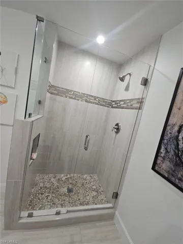 Bathroom featuring a shower stall and baseboards