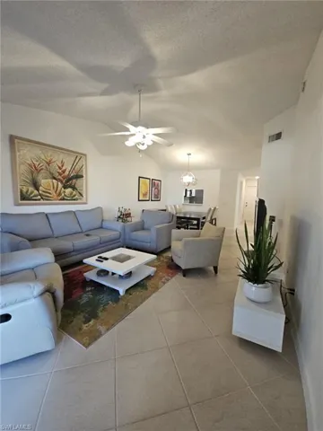 Tiled living room featuring a ceiling fan