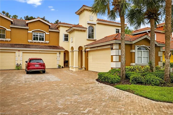 View of front of property with decorative driveway, an attached garage, stucco siding, and a tiled roof