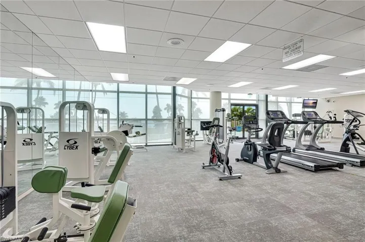 Exercise room with floor to ceiling windows looking out over pool and beach