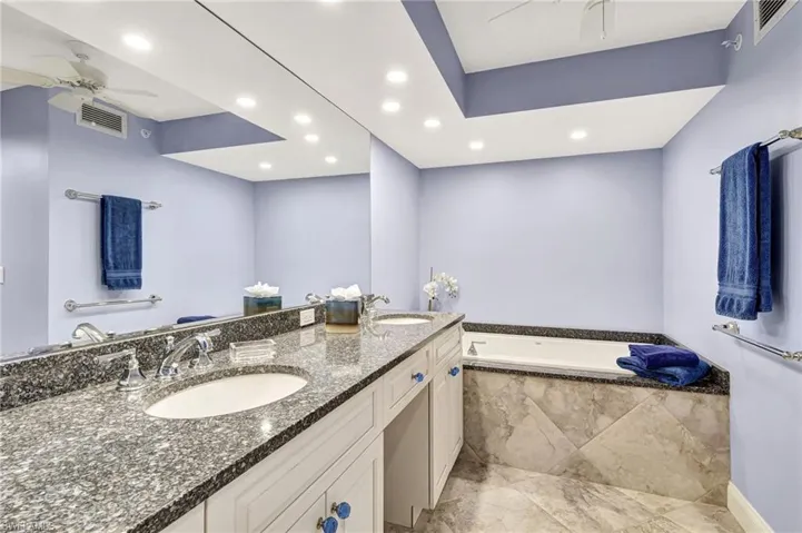 Bathroom featuring double sinks, granite vanity top as well as soaking tub