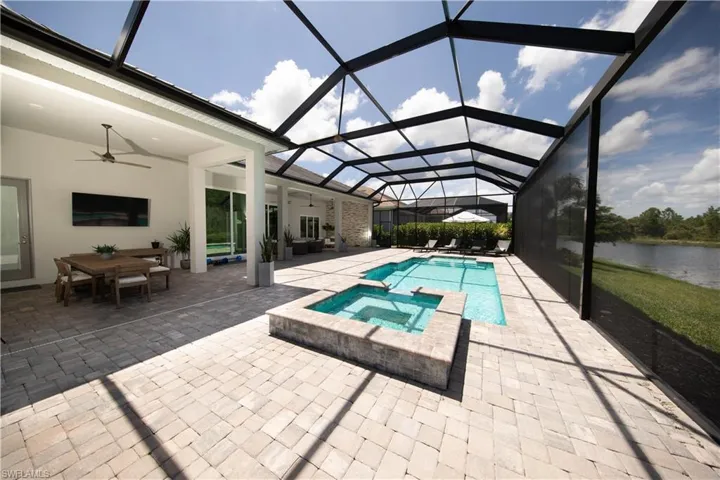 View of pool featuring a water view, inground pool and hot tub, a patio, ceiling fan