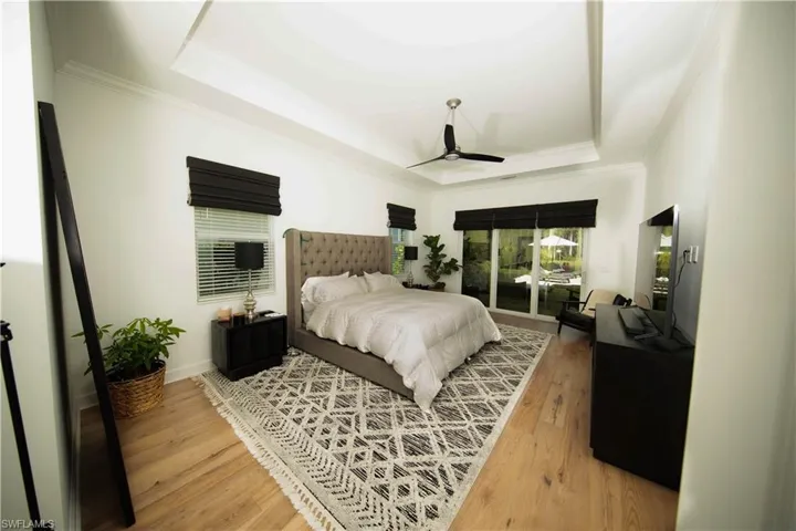 Primary Bedroom featuring light wood-type flooring, ornamental molding, and a tray ceiling