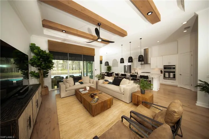 Living room with ceiling fan, ornamental molding, beamed ceiling, and light hardwood / wood-style flooring
