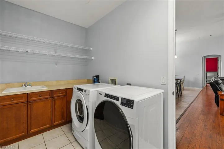 Clothes washing area featuring cabinets, separate washer and dryer, sink, and light wood-type flooring