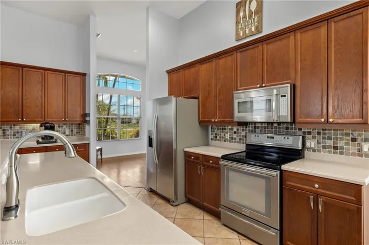 Kitchen with sink, appliances with stainless steel finishes, light wood-type flooring, and backsplash