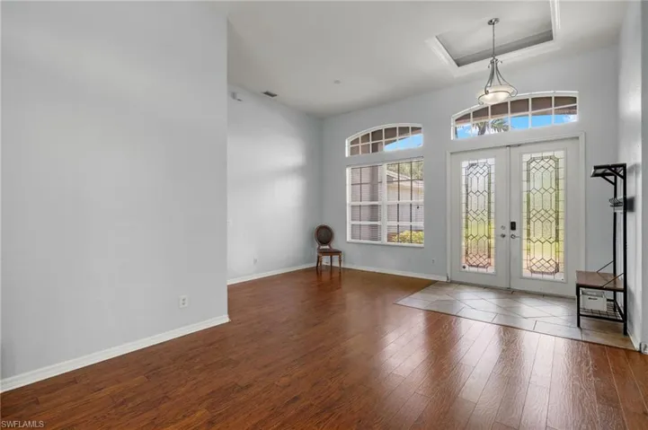 Entrance foyer with french doors, a tray ceiling, hardwood / wood-style floors, and a towering ceiling