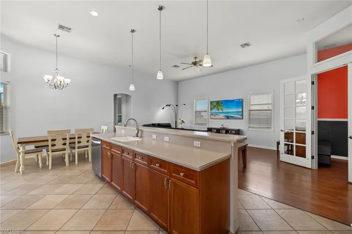 Kitchen featuring sink, hanging light fixtures, light tile patterned floors, an island with sink, and dishwasher