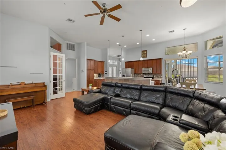 Living room with french doors, ceiling fan with notable chandelier, and hardwood / wood-style floors