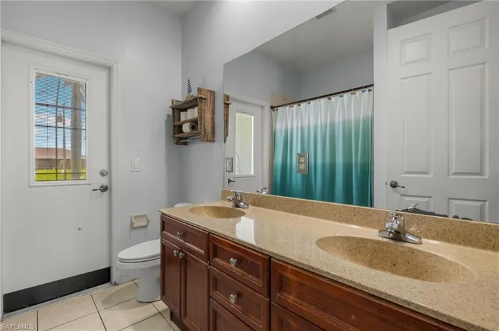 Bathroom featuring toilet, tile patterned floors, and double vanity