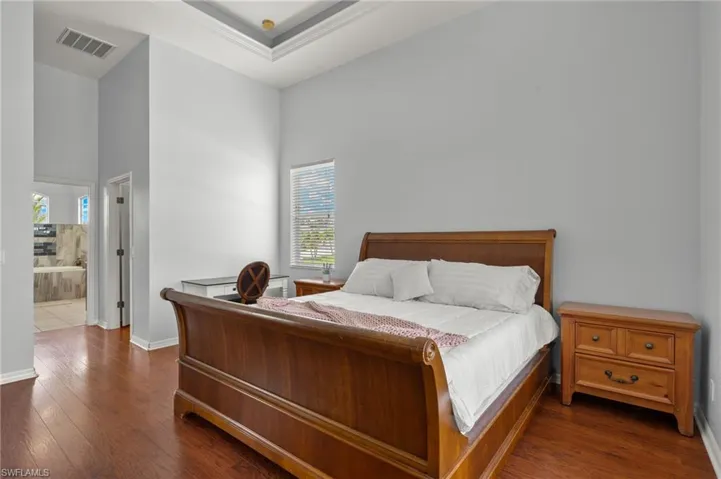 Bedroom with ensuite bath, dark hardwood / wood-style flooring, and a towering ceiling