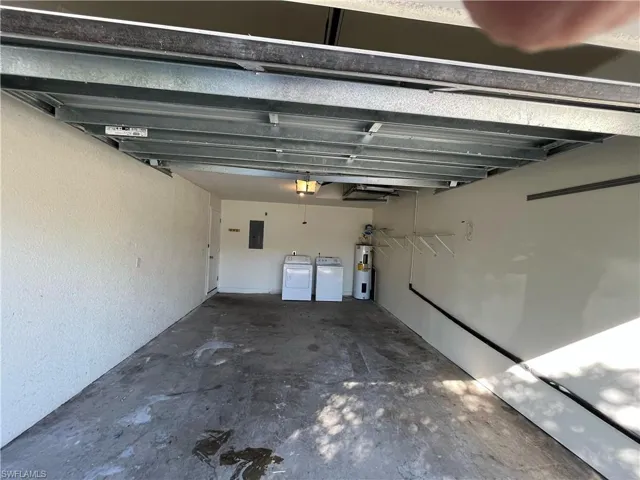 Garage with washer and dryer, electric water heater, electric panel, and a garage door opener