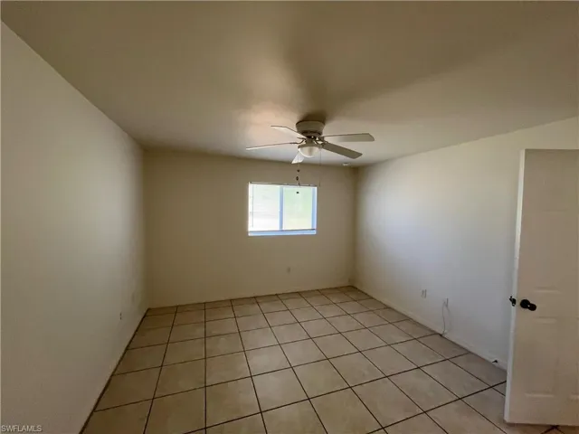 Empty room with light tile patterned floors and a ceiling fan