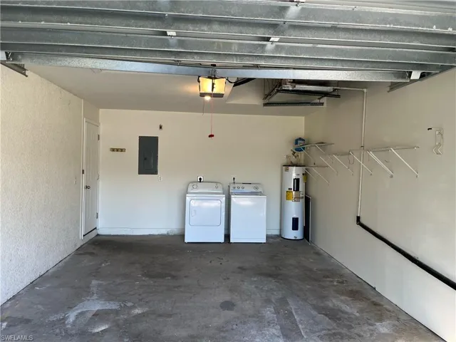 Garage featuring electric panel, water heater, washing machine and dryer, and a garage door opener