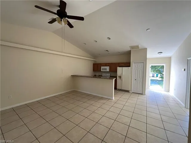 Kitchen featuring a peninsula, white appliances, brown cabinetry, open floor plan, and a ceiling fan