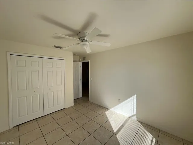 Unfurnished bedroom featuring a closet, ceiling fan, and light tile patterned floors