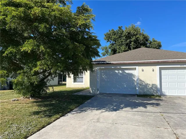 View of front facade featuring a front yard, stucco siding, driveway, and a shingled roof