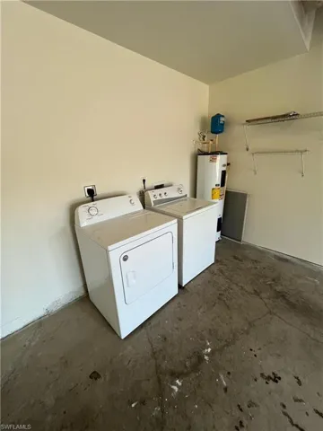 Laundry room featuring unfinished concrete flooring, water heater, and separate washer and dryer