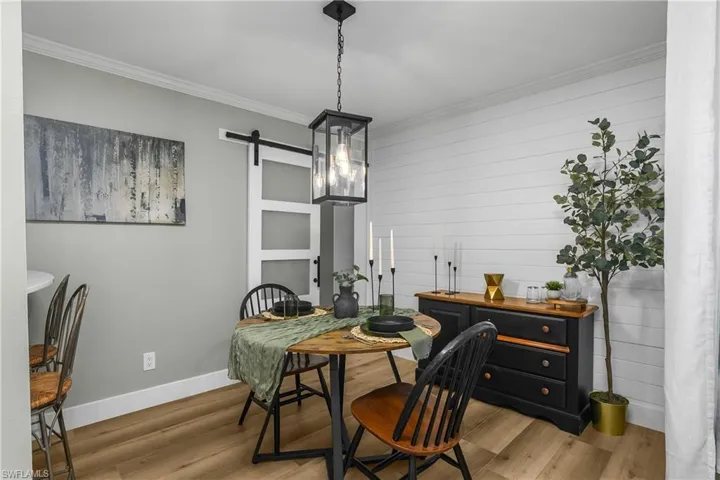 Dining space with a barn door, shiplap accent wall, and ornamental molding