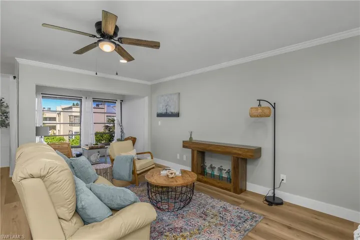 Living room with crown molding, Luxruy Vinyln wide plank flooring, and ceiling fan