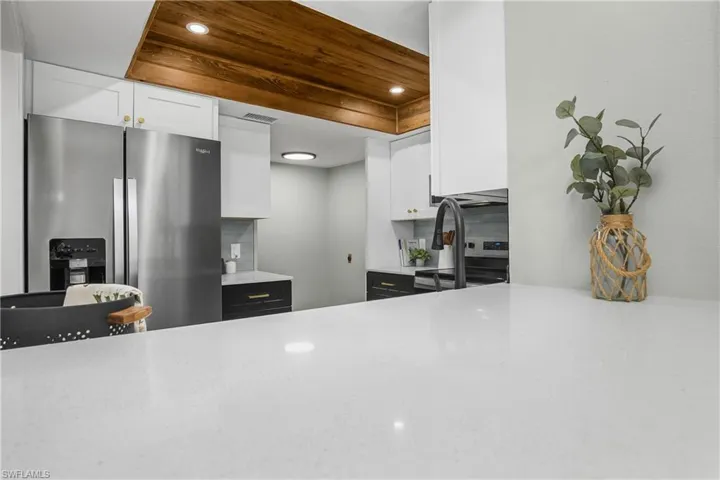 Kitchen featuring white cabinets, light stone countertops, stainless steel refrigerator with ice dispenser, and recessed lighting