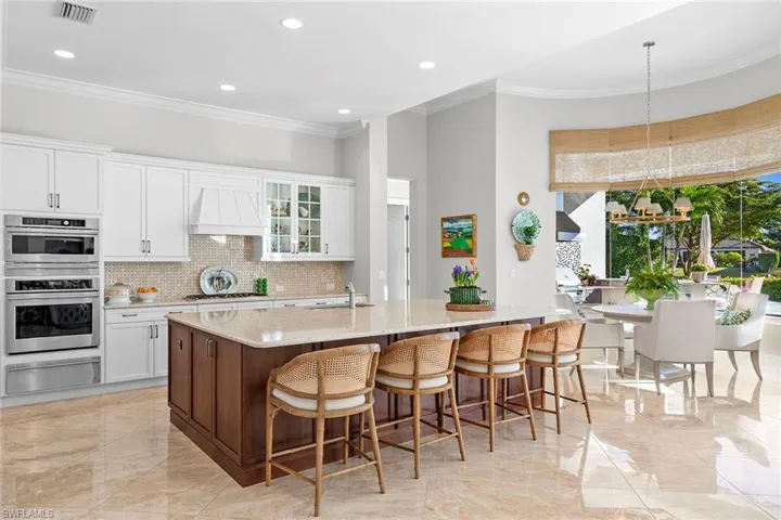 Kitchen with glass insert cabinets, white cabinetry, a breakfast bar area, ornamental molding, and light stone counters