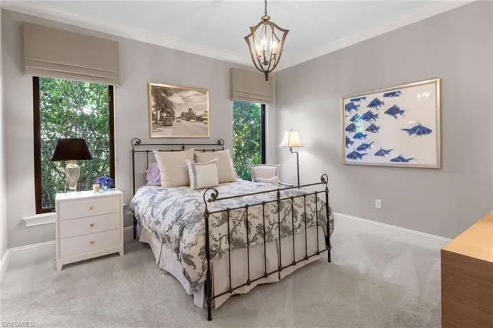 Carpeted bedroom with crown molding and a chandelier