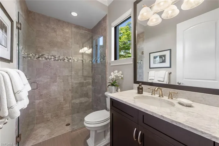 Bathroom with vanity, a shower stall, and a chandelier