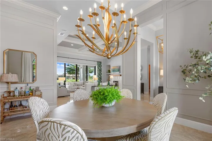 Dining area with a decorative wall, crown molding, a chandelier, coffered ceiling, and wainscoting