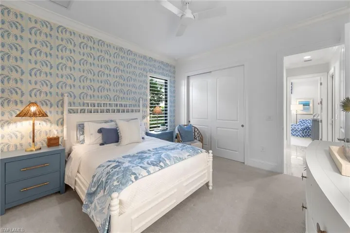 Bedroom featuring ornamental molding, a closet, wallpapered walls, light colored carpet, and ceiling fan