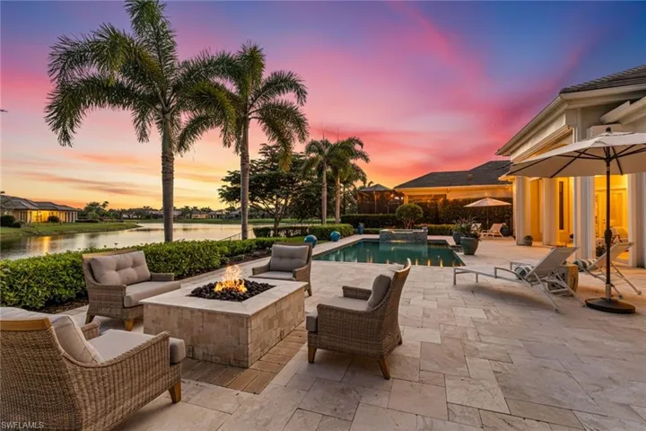 View of patio / terrace with a pool with connected hot tub, an outdoor living space with a fire pit, and a water view