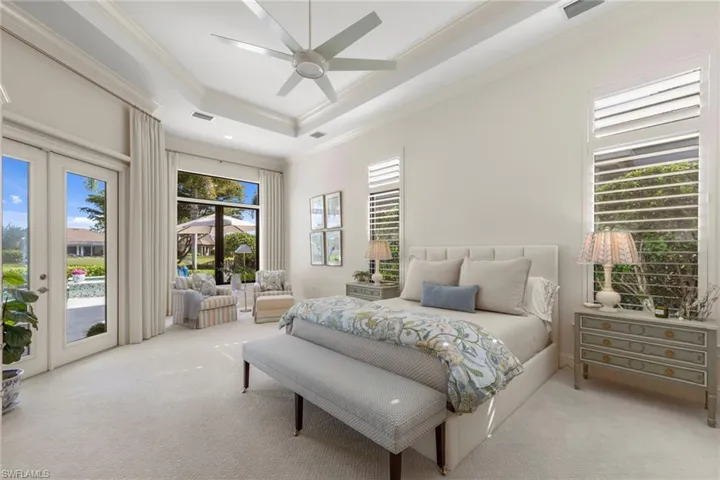 Bedroom with access to exterior, crown molding, a raised ceiling, a ceiling fan, and carpet