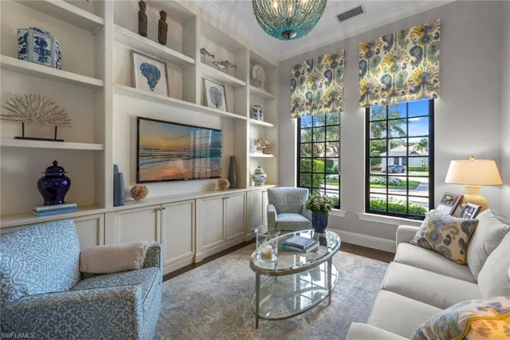 Living area featuring built in shelves, crown molding, wood finished floors, and a chandelier
