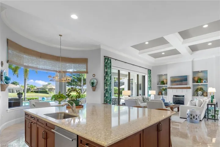 Kitchen with a fireplace, light stone counters, pendant lighting, brown cabinetry, and recessed lighting