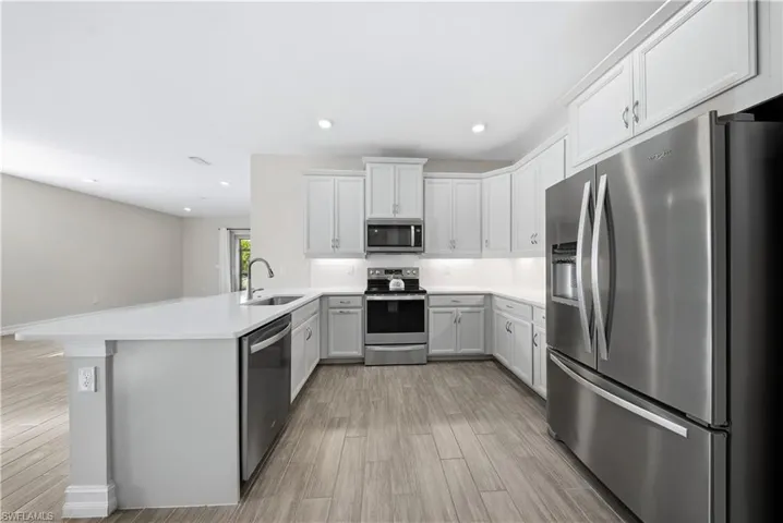 Kitchen featuring stainless steel appliances, a peninsula, light wood-style flooring, tasteful backsplash, and recessed lighting