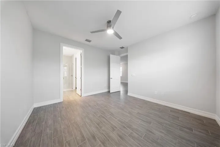 Unfurnished bedroom featuring wood tiled floors, ceiling fan, and connected bathroom