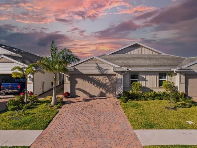Single story home with board and batten siding, an attached garage, a yard, and decorative driveway