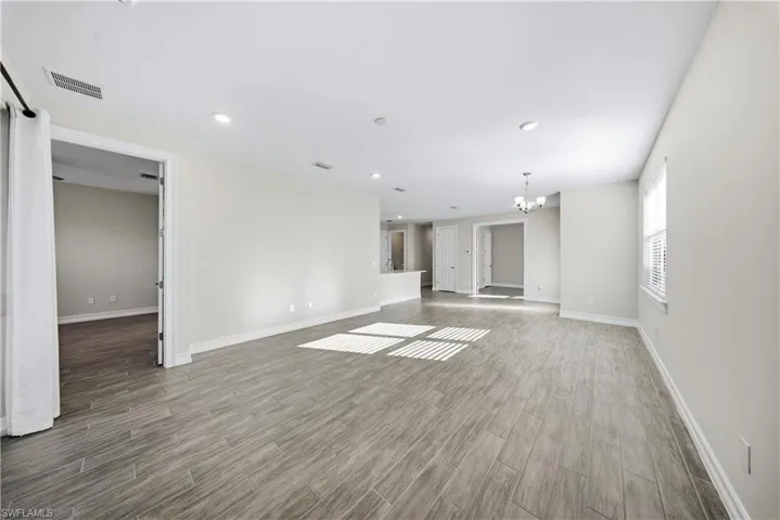 Unfurnished room with dark wood finished floors and a chandelier