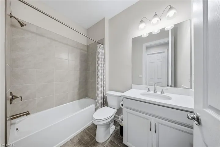 Full bath featuring vanity, shower / bath combo, and wood finish floors