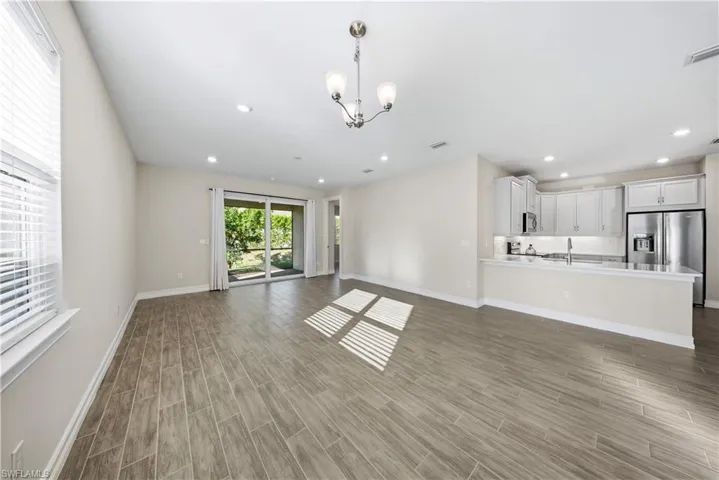 Unfurnished living room with wood finish floors and hanging lights