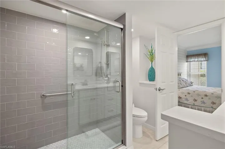 Ensuite bathroom with tile patterned flooring, toilet, ensuite bath, and a stall shower