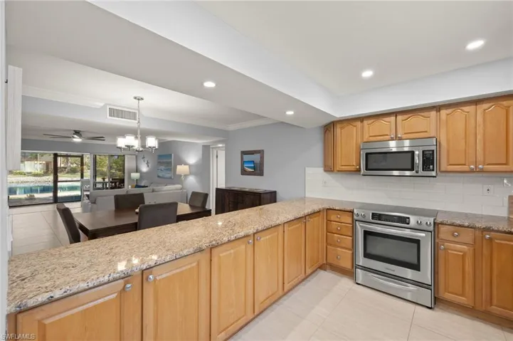 Kitchen with light tile patterned floors, light stone countertops, visible vents, and stainless steel appliances