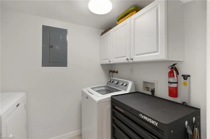 Laundry room with baseboards, cabinet space, electric panel, and washing machine and dryer