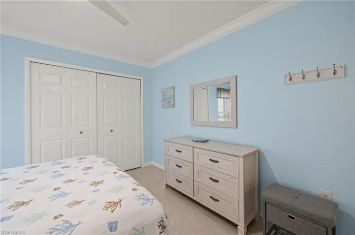 Bedroom featuring crown molding, baseboards, a closet, light wood finished floors, and a ceiling fan